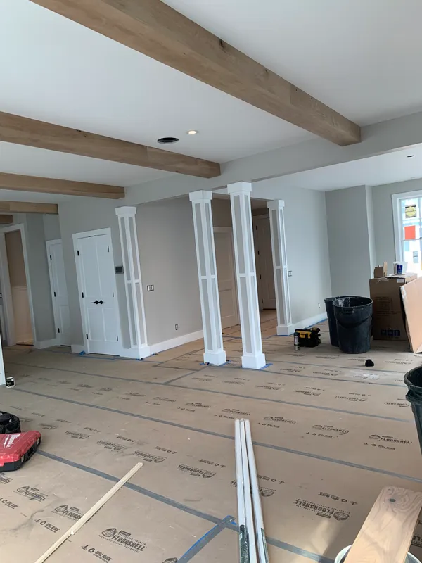 Interior of a home under construction with wooden beams and white pillars.