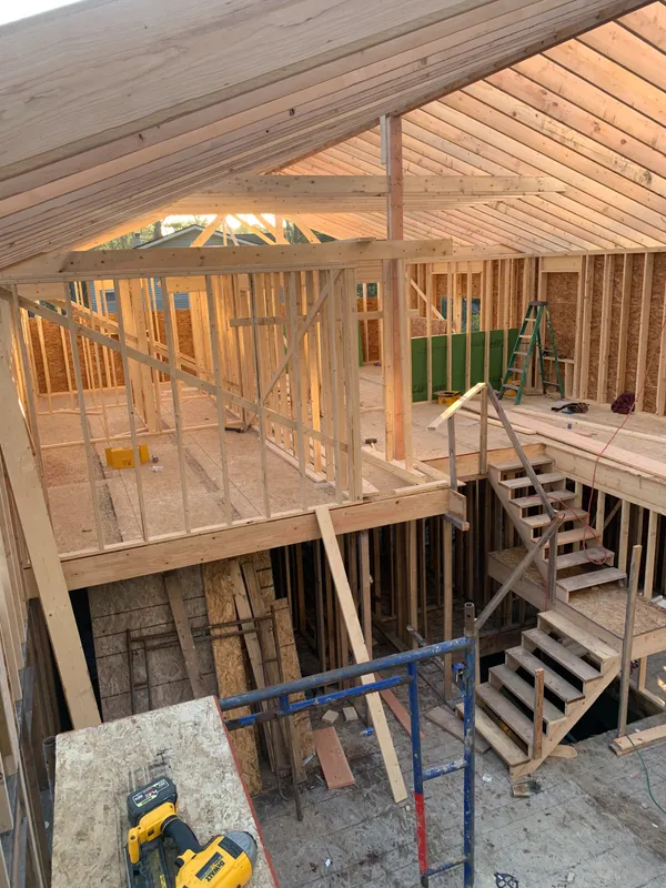 Interior of a residential house under construction with wooden framing and stairs.