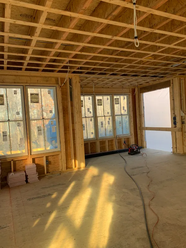 Interior of a residential house under construction with wooden framing and windows.