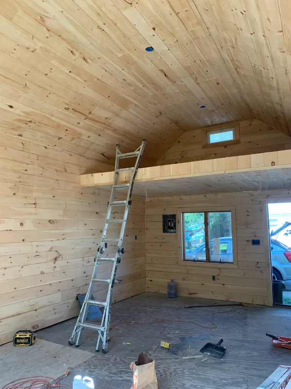 Interior of a wood-framed building under construction with an extension ladder.